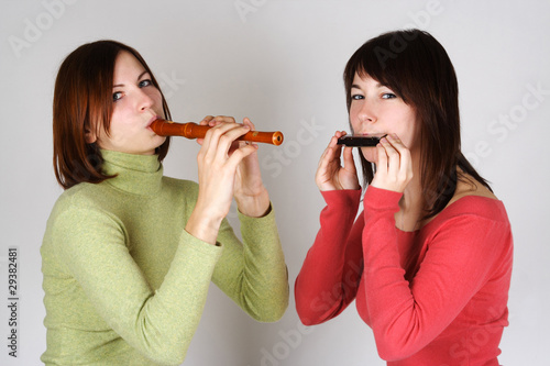 Photo: two brunette girls in bright shirts playing on flute and harp, l two brunette girls in bright shirts playing on flute and harp, l