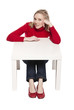 Young woman sitting at funny small desk