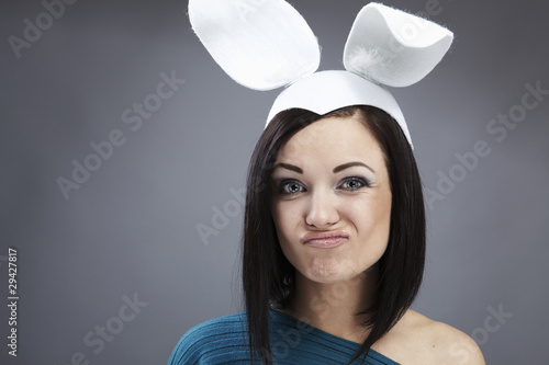 Foto: Funny Brunette in a bright sweater with rabbit ears on her head. Funny Brunette in a bright sweater with rabbit ears on her head.