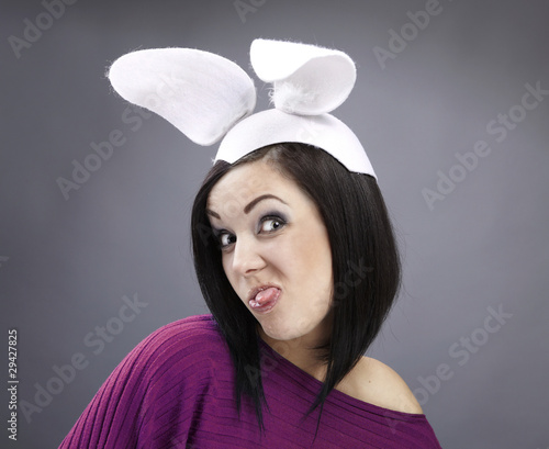 Photo: Funny Brunette in a bright sweater with rabbit ears on her head. Funny Brunette in a bright sweater with rabbit ears on her head.