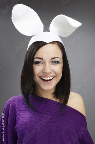Foto: Funny Brunette in a bright sweater with rabbit ears on her head. Funny Brunette in a bright sweater with rabbit ears on her head.