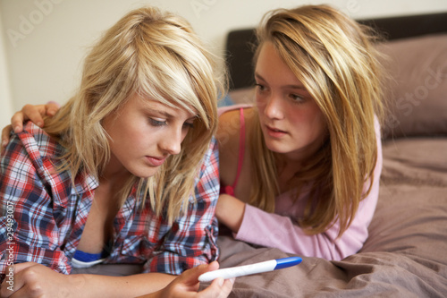 Photo: Two Teenage Girls Lying On Bed Looking At Pregnancy Testing Kit Two Teenage Girls Lying On Bed Looking At Pregnancy Testing Kit