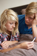 Two Teenage Girls Lying On Bed Looking At Pregnancy Testing Kit