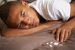 Depressed Teenage Boy Lying In Bedroom With Pills