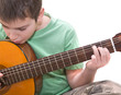 caucasian boy practicing; playing acoustic guitar;