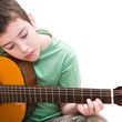 caucasian boy practicing; playing acoustic guitar