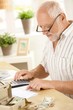 Older man using calculator at home Older man using calculator at home