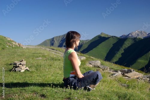 Photo: Woman sitting on grass in mountains relaxing Woman sitting on grass in mountains relaxing