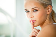 Portrait of young woman with finger on lips, at home