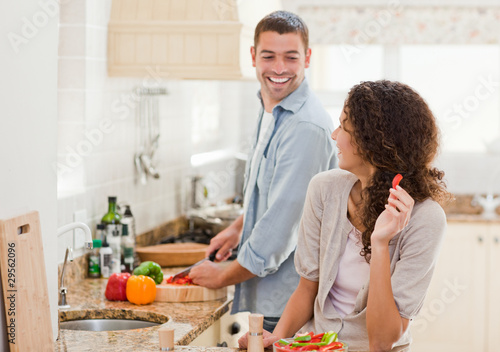 Photo: Beautiful woman looking at her husband who is cooking Beautiful woman looking at her husband who is cooking