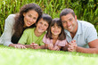 Photo: Happy family lying down in the garden Happy family lying down in the garden