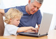 Lovely boy and his grandfather looking at their laptop