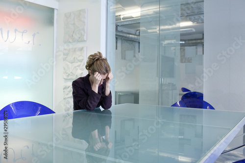 Photo: Young businesswoman in conference room crying Young businesswoman in conference room crying