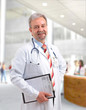 Happy smiling mature doctor writing on clipboard Happy smiling mature doctor writing on clipboard