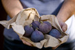 A man holding a paper bag containing fresh figs