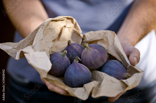 Photo: A man holding a paper bag containing fresh figs A man holding a paper bag containing fresh figs