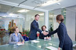 Businessman and businesswoman shaking hands in conference room