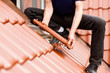 Dachdecker deckt Dach mit Dachziegel ein