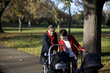 Two mothers looking at their babies in buggies in the park