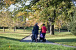 Two mothers pushing their buggies in the park, rear view