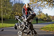A mother looking at her babies in a buggy in the park