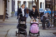 Two mothers pushing their buggies in the street
