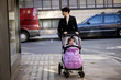 A mother pushing a buggy, looking in a shop window