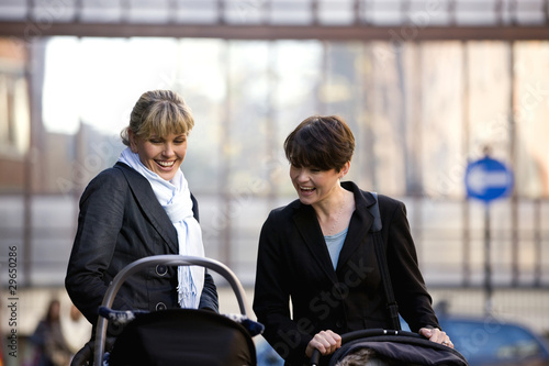 Photo: Two mothers pushing their buggies in the street Two mothers pushing their buggies in the street