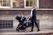 A mother pushing a double buggy in the street