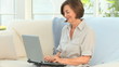 Retired woman working on a computer on her sofa