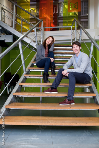 Photo: Man and woman sitting on stairs in office Man and woman sitting on stairs in office