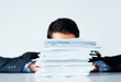Businessman hiding behind paperwork