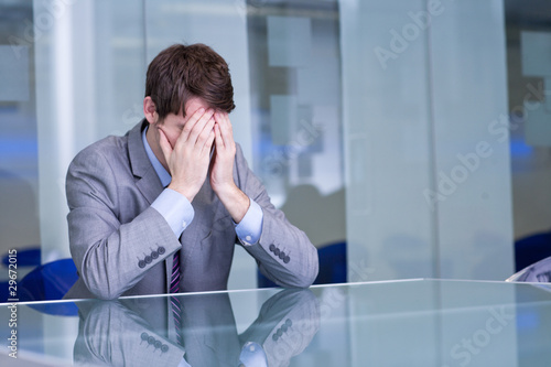 Photo: Depressed businessman sitting at conference table Depressed businessman sitting at conference table