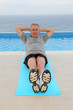 Senior man doing exercises by a swimming-pool