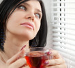 Thoughtful brunette girl drinking tea at the window