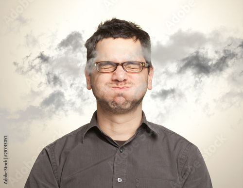 Foto: Young man holding his breath among black clouds Young man holding his breath among black clouds