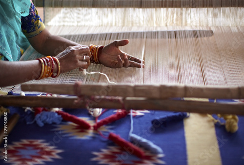 Photo: Woman hand weaving a carpet with a manual loom in India Woman hand weaving a carpet with a manual loom in India