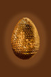 Golden egg decorated with spangles on brown background Golden egg decorated with spangles on brown background