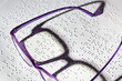 Brille und Buch in Blindenschrift. Braille