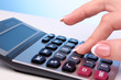 Fingers and calculator on blue background