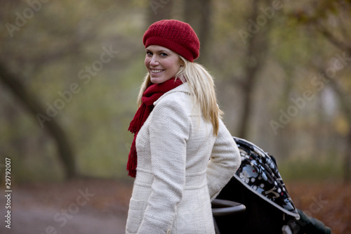 Photo: A young mother pushing a stroller in the park A young mother pushing a stroller in the park