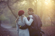 A young couple pushing a stroller in the park, rear view