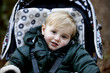 Portrait of a young boy sitting in a stroller, smiling
