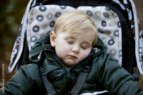 Photo: Portrait of a young boy sitting in a stroller, sleeping Portrait of a young boy sitting in a stroller, sleeping