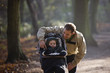 A young father with his son in a stroller in the park