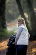 A young mother pushing a stroller in the park, smiling