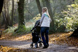 A young mother pushing a stroller in the park, smiling