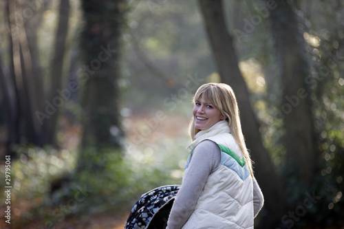 Photo: A young mother pushing a stroller in the park, smiling A young mother pushing a stroller in the park, smiling