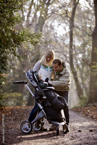 Photo: A young couple smiling at their son in a stroller A young couple smiling at their son in a stroller