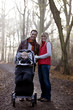 A young couple pushing a stroller in the park, smiling